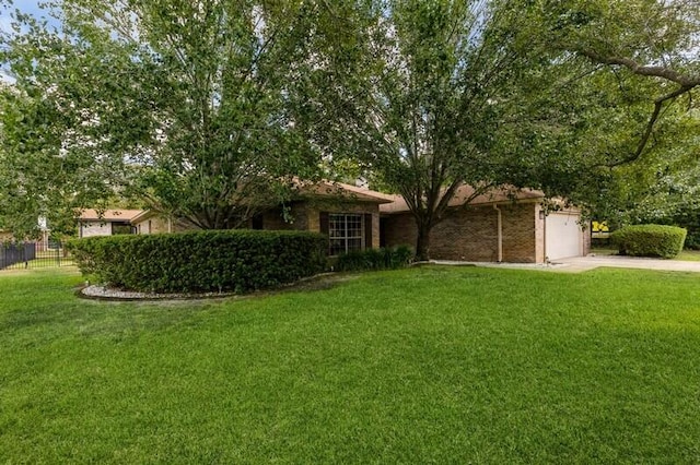 view of front of house featuring an attached garage, concrete driveway, a front lawn, and fence