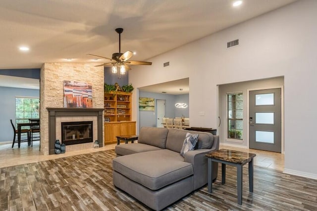 living room with a fireplace, dark hardwood / wood-style flooring, high vaulted ceiling, and ceiling fan