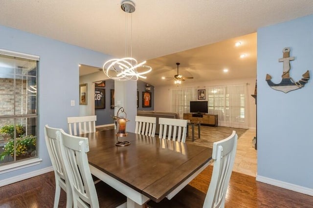 dining area featuring ceiling fan with notable chandelier and dark hardwood / wood-style floors