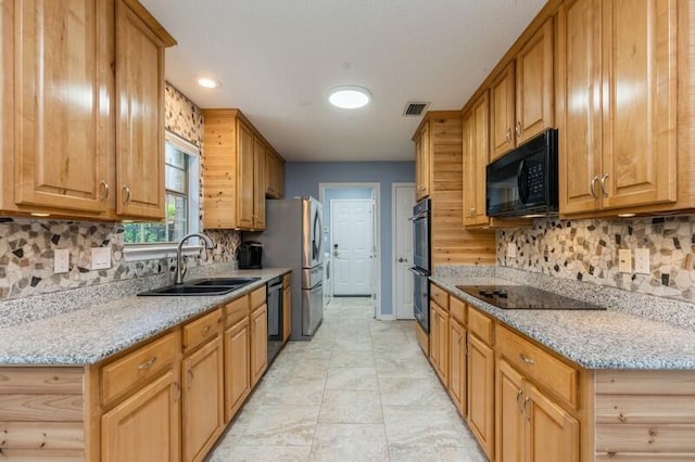 kitchen with black appliances, light stone counters, backsplash, and sink