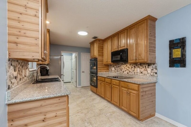 kitchen with backsplash, light tile patterned floors, black appliances, light stone counters, and sink