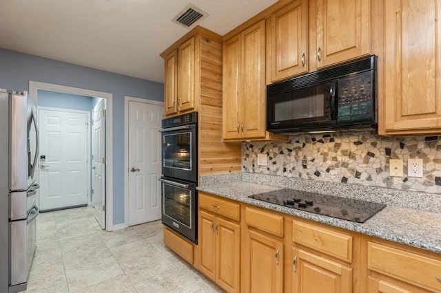 kitchen with black appliances, light stone counters, light tile patterned floors, and tasteful backsplash