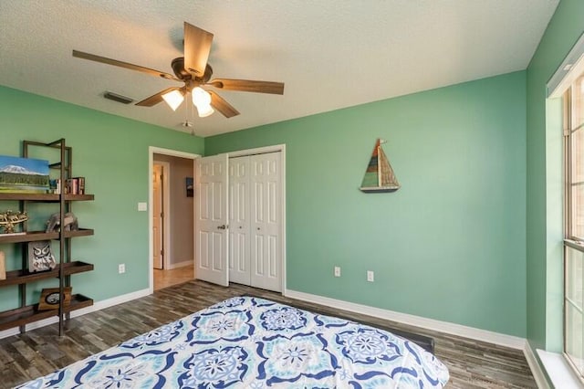 bedroom with dark wood-type flooring, a closet, ceiling fan, and a textured ceiling