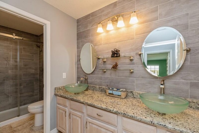 bathroom featuring toilet, walk in shower, vanity, backsplash, and tile walls