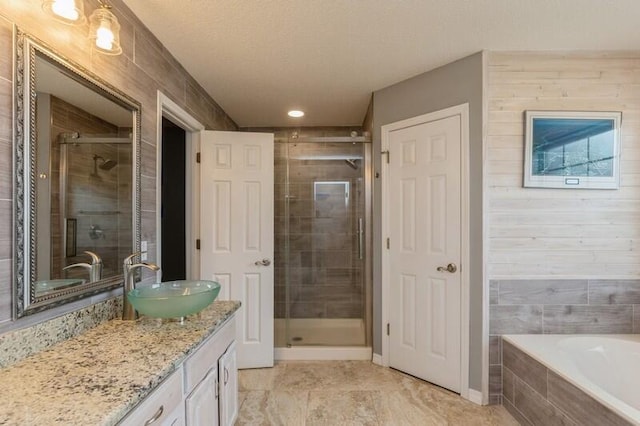 bathroom featuring tile patterned flooring, shower with separate bathtub, tile walls, vanity, and a textured ceiling