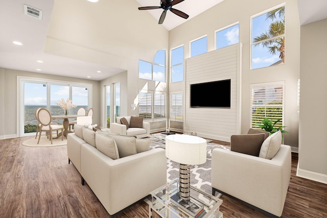 living room with ceiling fan, dark hardwood / wood-style flooring, and a high ceiling