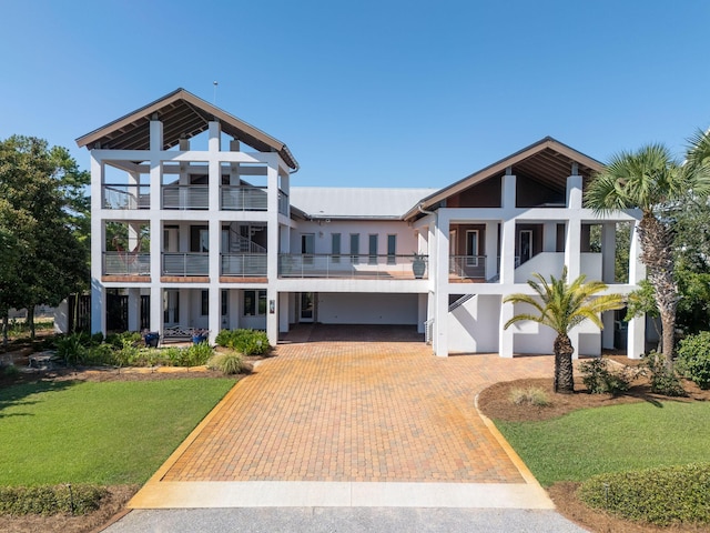 view of front of home with a balcony, a garage, decorative driveway, stucco siding, and a front lawn