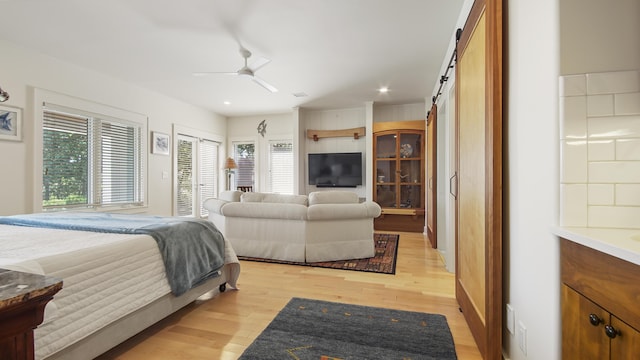 bedroom featuring light wood-style floors, a barn door, a ceiling fan, and recessed lighting