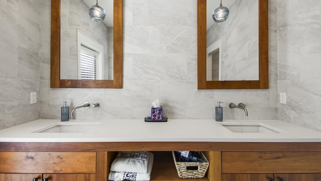 bathroom with a sink, tile walls, and double vanity