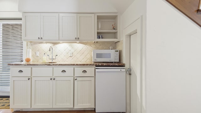 kitchen featuring white appliances, backsplash, a sink, and white cabinetry