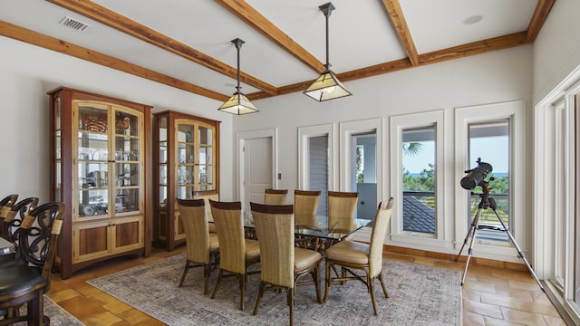 dining area featuring visible vents, stone finish flooring, and beam ceiling