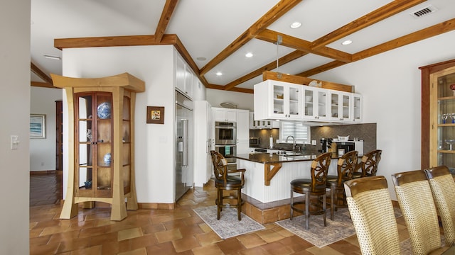 kitchen featuring backsplash, visible vents, a peninsula, and beam ceiling