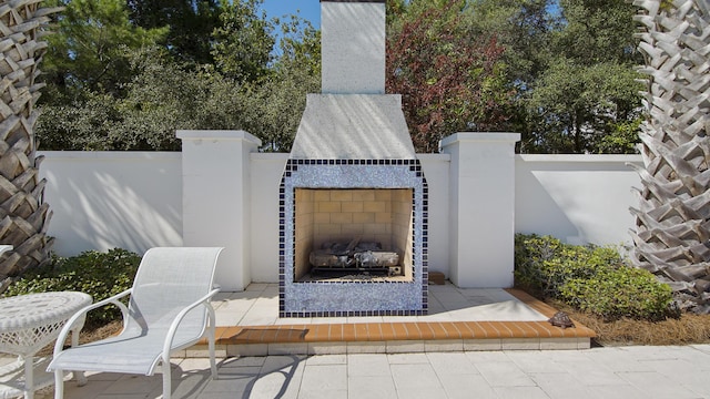 view of patio featuring fence and a tiled fireplace