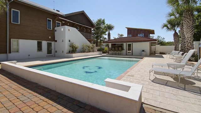 pool featuring outdoor dry bar, a storage structure, fence, an outdoor structure, and a patio area