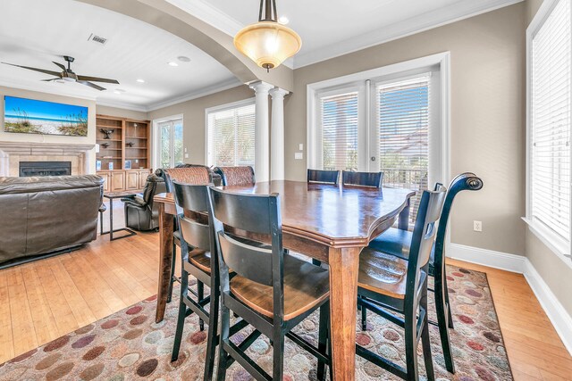 dining area featuring a healthy amount of sunlight, ceiling fan, a fireplace, and light hardwood / wood-style flooring