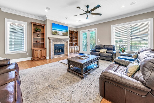 living room featuring a fireplace, crown molding, ceiling fan, and light hardwood / wood-style floors