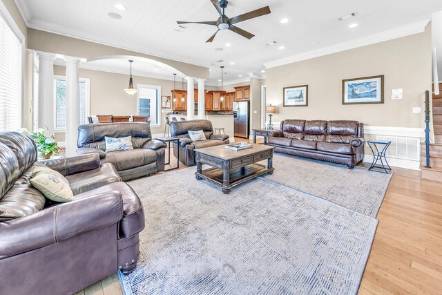 living room with ornamental molding, light wood-type flooring, and ornate columns