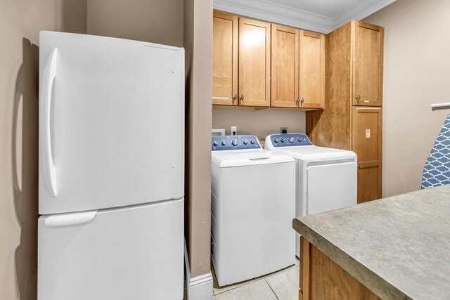 clothes washing area with light tile patterned flooring, ornamental molding, cabinets, and washer and dryer