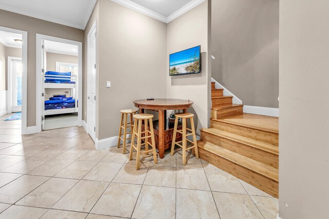 entryway with crown molding and light tile patterned floors