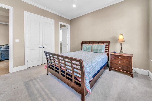 carpeted bedroom with crown molding and a closet