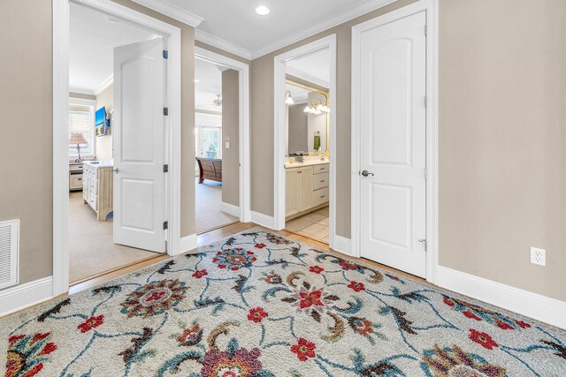 hall featuring a notable chandelier, light colored carpet, and crown molding