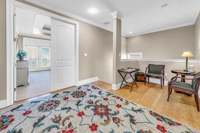 entrance foyer featuring light hardwood / wood-style flooring, ornamental molding, a tray ceiling, and ornate columns