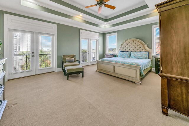 carpeted bedroom featuring a tray ceiling, crown molding, access to outside, and ceiling fan