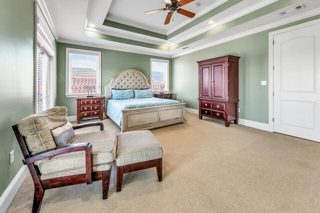 bedroom with a tray ceiling, light carpet, crown molding, and ceiling fan