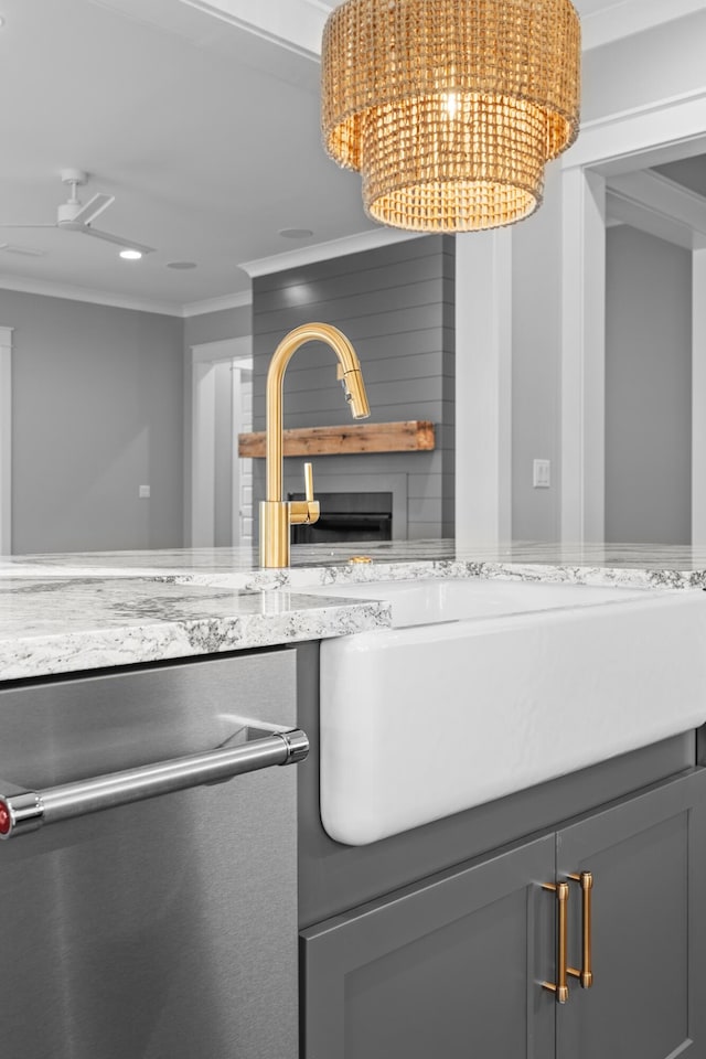 kitchen featuring stainless steel dishwasher, a notable chandelier, crown molding, gray cabinets, and a fireplace