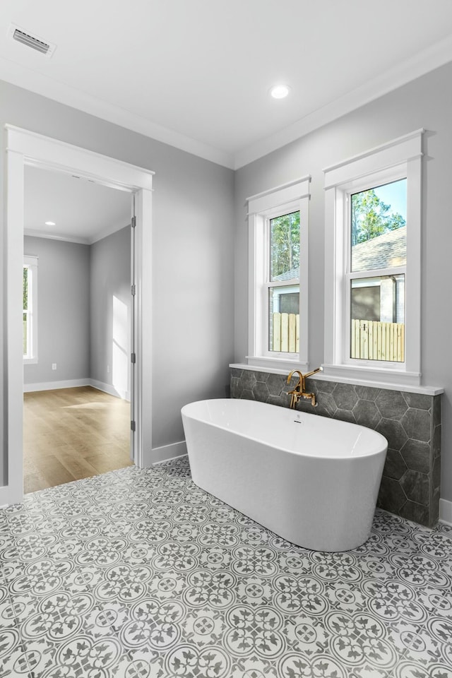 bathroom featuring tile patterned floors, crown molding, and a tub