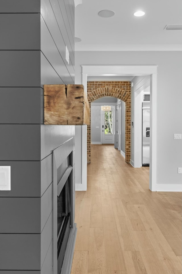 corridor featuring light wood-type flooring and ornamental molding