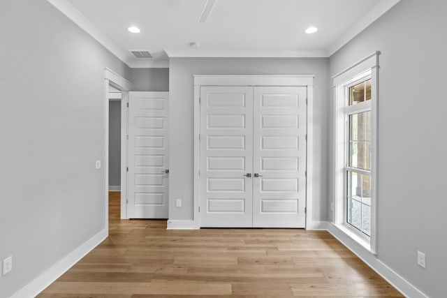 unfurnished bedroom featuring a closet, light hardwood / wood-style flooring, multiple windows, and crown molding