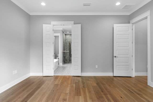 unfurnished bedroom featuring wood-type flooring, crown molding, and connected bathroom