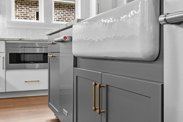 room details featuring stainless steel oven and wood-type flooring