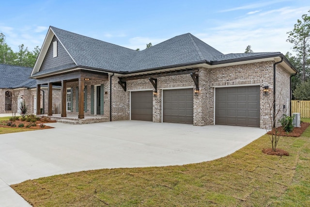 view of front of house with covered porch, a garage, central AC unit, and a front yard