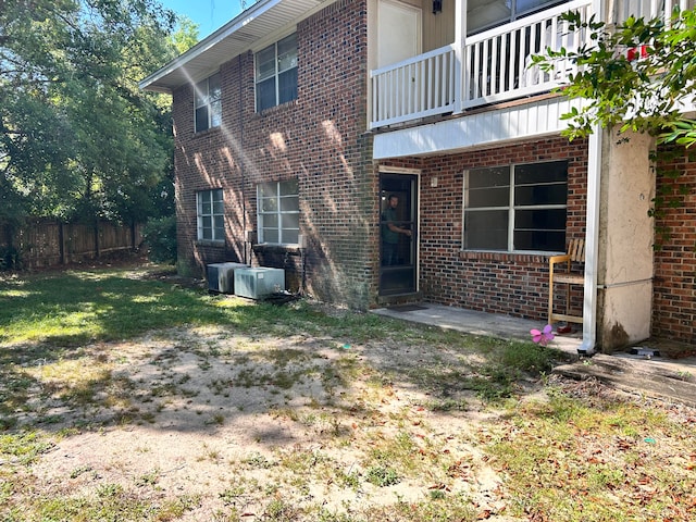 back of house with a balcony and a lawn