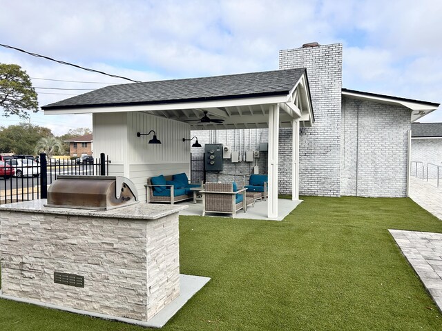 exterior space featuring an outdoor kitchen, a yard, ceiling fan, an outdoor living space, and a patio