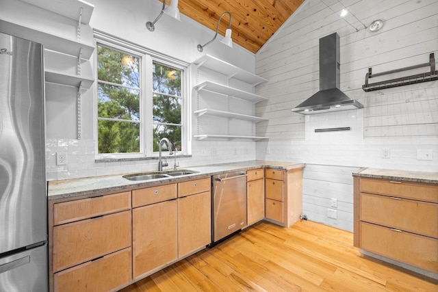 kitchen with sink, decorative backsplash, light stone countertops, appliances with stainless steel finishes, and wall chimney range hood