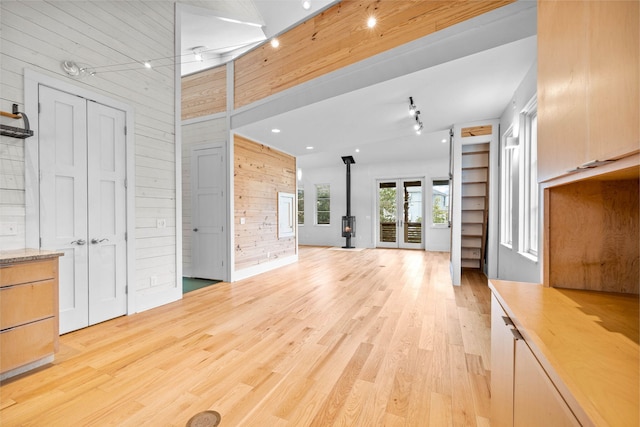 unfurnished living room with light hardwood / wood-style flooring, wood walls, and rail lighting