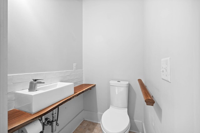 bathroom featuring toilet and backsplash