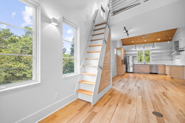 stairs featuring sink, wood-type flooring, and track lighting