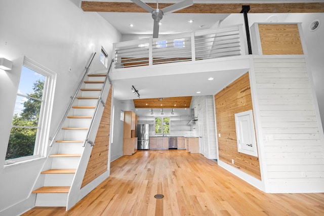 entrance foyer with light hardwood / wood-style flooring, a high ceiling, and wood walls