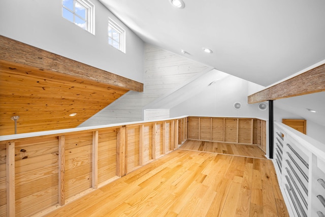 additional living space featuring lofted ceiling, wood walls, and light wood-type flooring