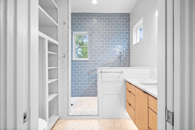 bathroom with tile walls, walk in shower, a wealth of natural light, and vanity