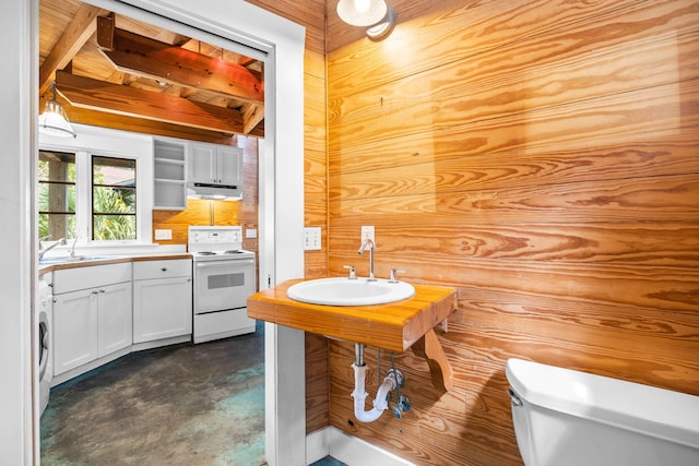 bathroom featuring concrete flooring, toilet, beamed ceiling, and sink