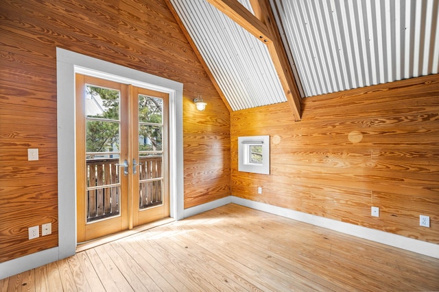 interior space featuring lofted ceiling with beams, hardwood / wood-style flooring, wood walls, and french doors