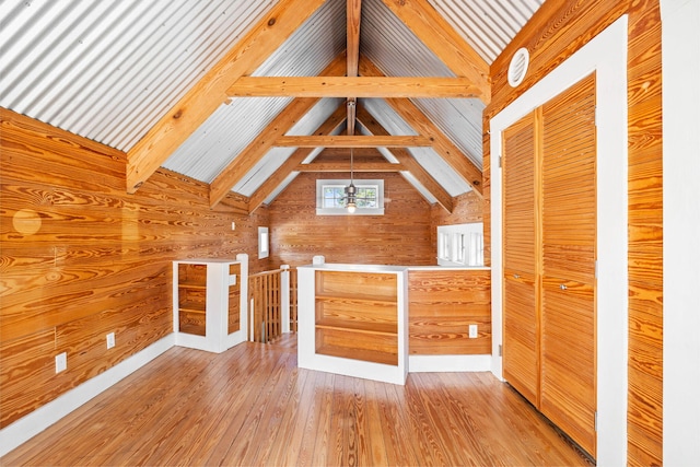 bonus room with light hardwood / wood-style flooring, wooden walls, and lofted ceiling with beams