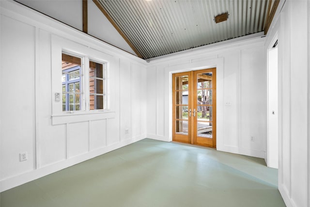 spare room featuring french doors, a healthy amount of sunlight, and concrete floors