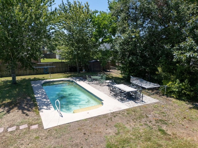 view of swimming pool with a yard, a storage unit, and a patio area