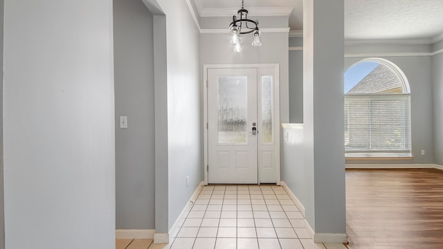 entrance foyer featuring crown molding, a textured ceiling, light hardwood / wood-style flooring, and an inviting chandelier